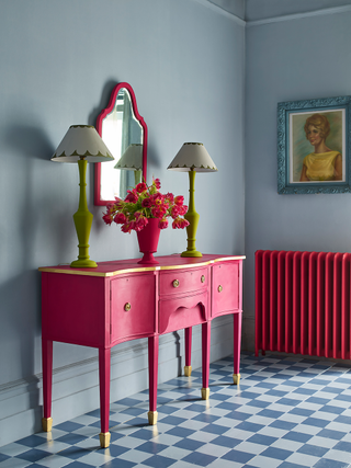 Blue and white checkerboard floor with a pink console table