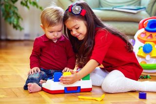 Two children play together with a toy.