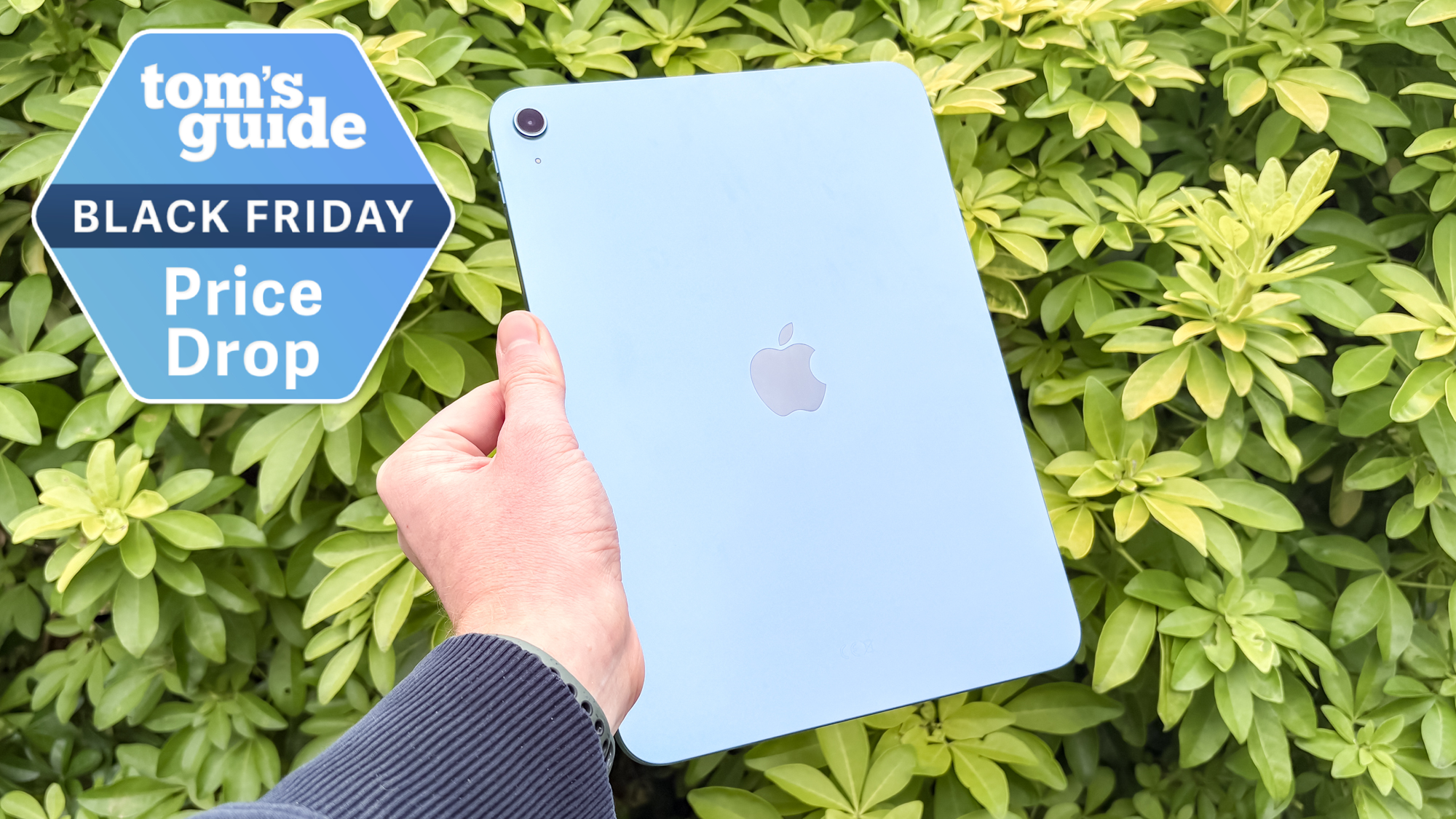 iPad 11 held in hand with green bush behind with Tom&#039;s Guide Black Friday Price Drop badge
