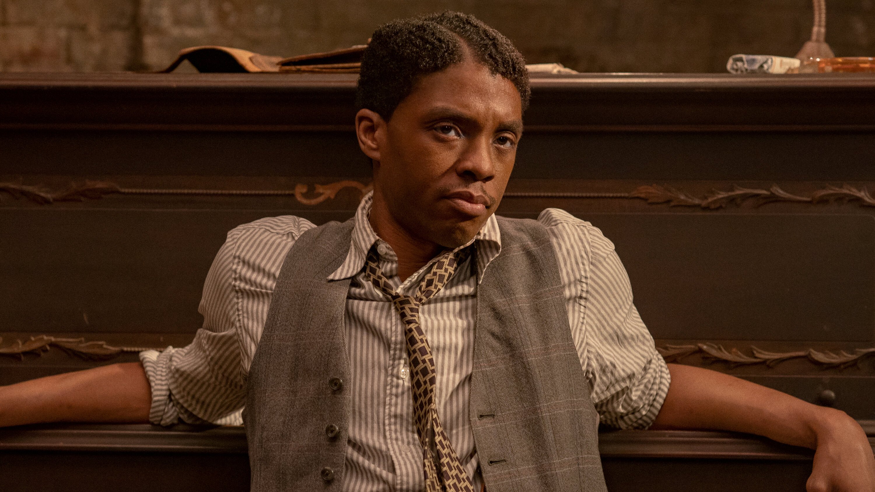 Chadwick Boseman leans back against a piano in Ma Rainey&#039;s Black Bottom.