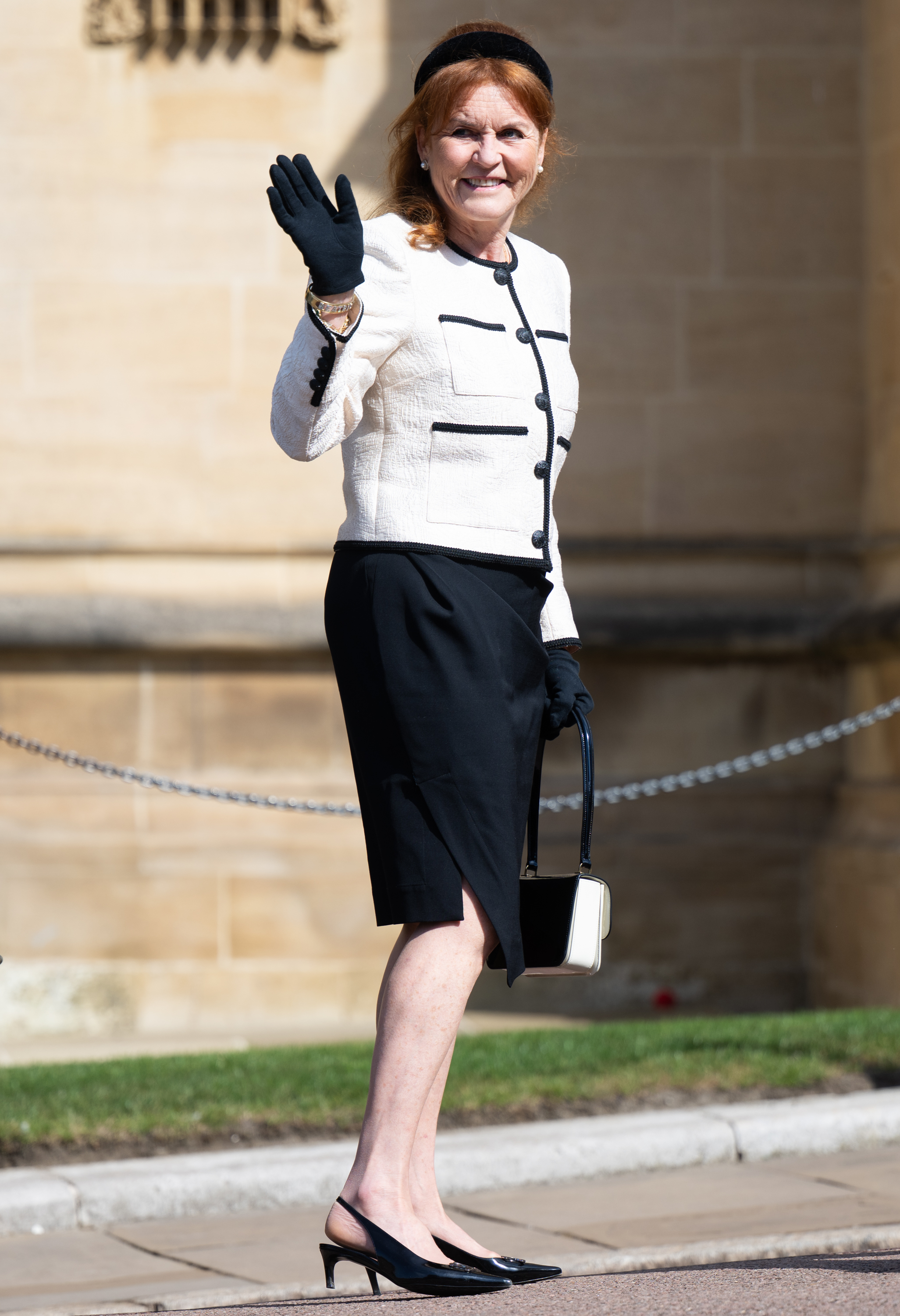 Sarah Ferguson wearing a white blazer and black skirt and waving