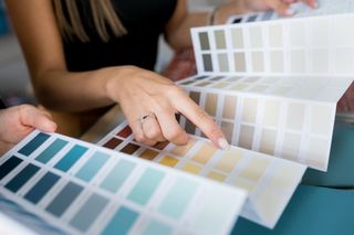 a woman pointing to a paint colour on a paint colour guide.