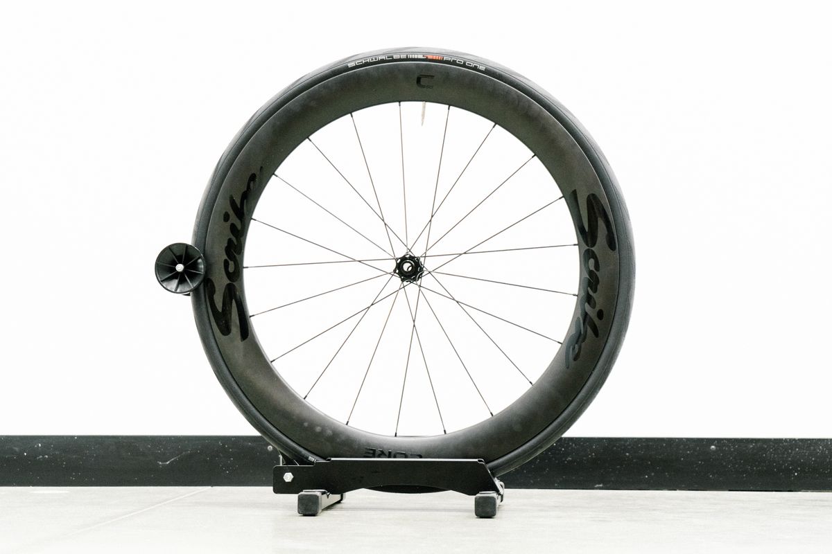 An aero road wheel stands against a white wall
