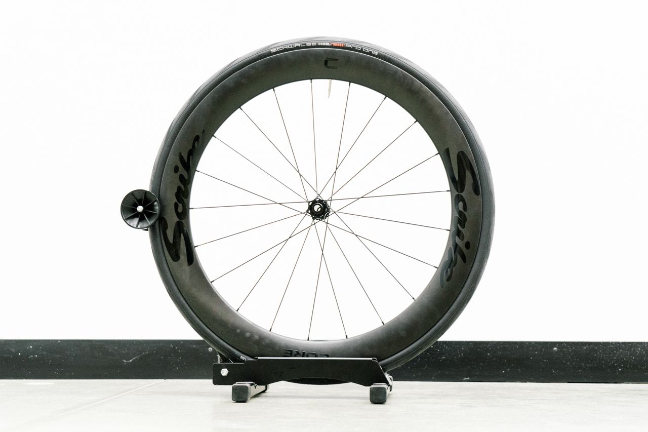 An aero road wheel stands against a white wall