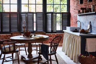 Industrial kitchen with exposed brick and black shutters rustic sink with skirt and wooden dining table
