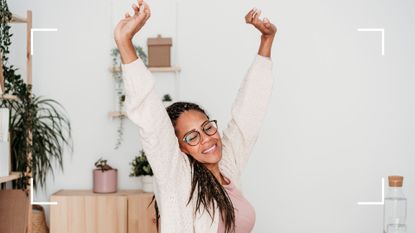 Woman reaching hands up towards the ceiling after using one of the best stretching apps in 2024
