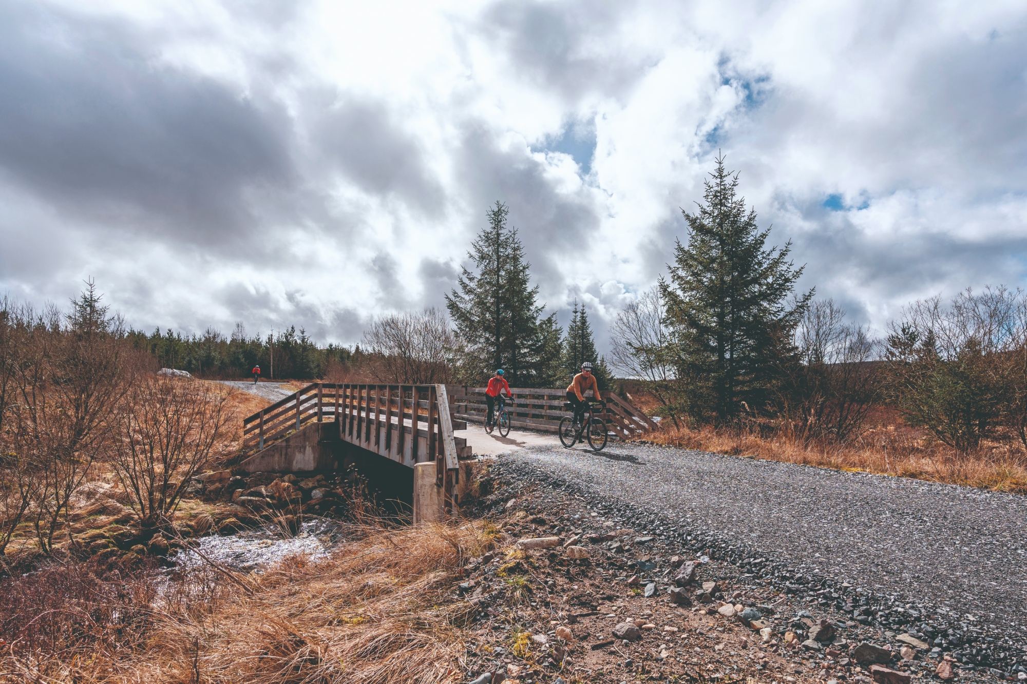 Two gravel riders cross a bridge in Scotland