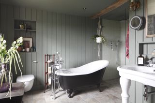 traditional style bathroom with sage green pannelling, a black freestanding bath and other features