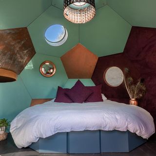 Inside of a holiday home pod with bed and colourful walls