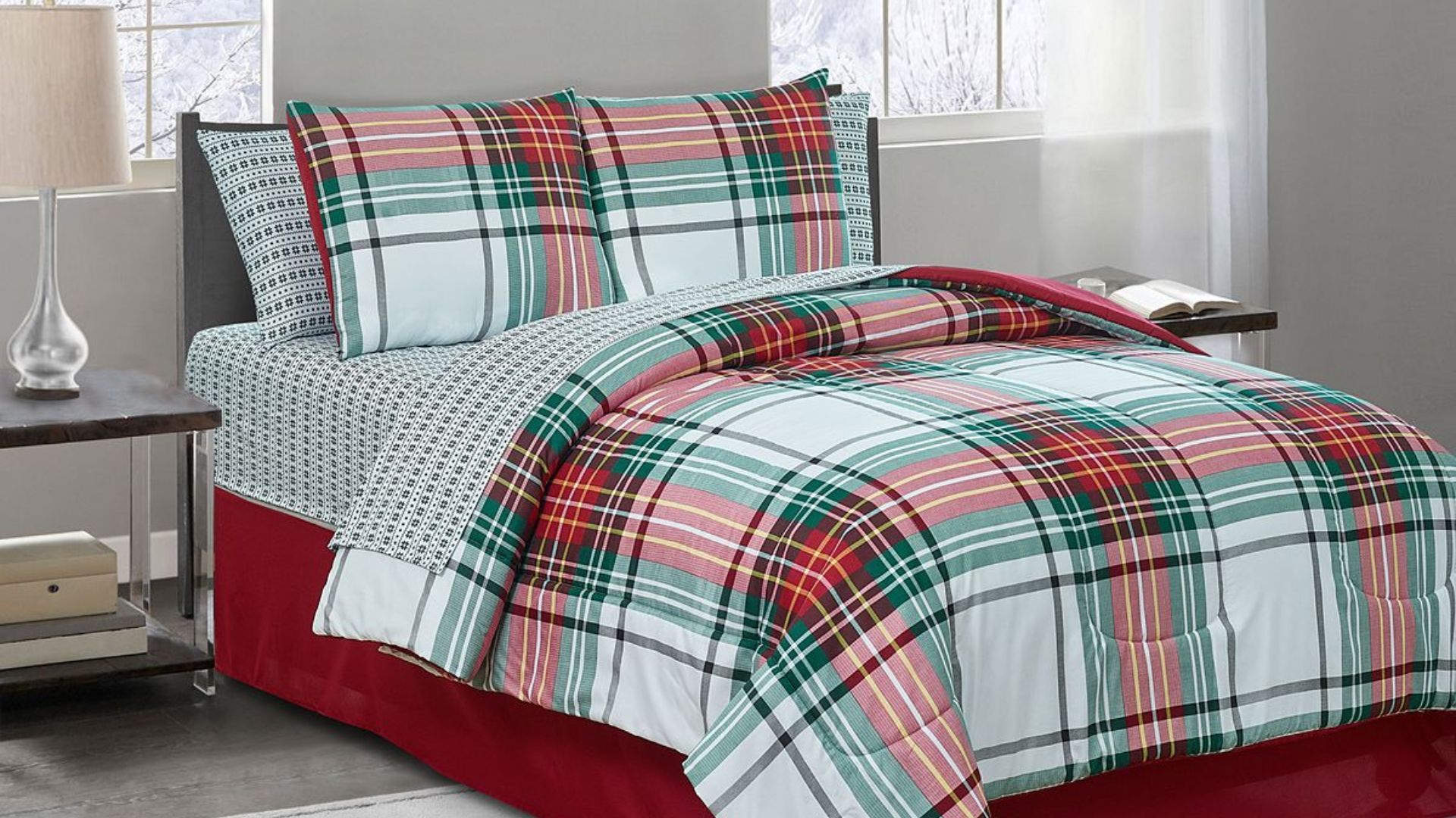 A made up bed with a green and red reversible Christmas bedding 8-piece comforter set.