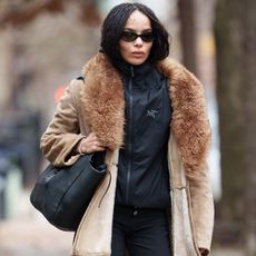 Zoe kravitz wears a fur-trimmed jacket with a black windbreaker.