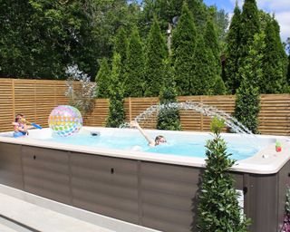 swim spa by Hydrolife with slatted fence and kids playing