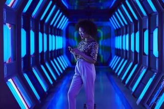 A woman with her phone standing in a room with blue lights on