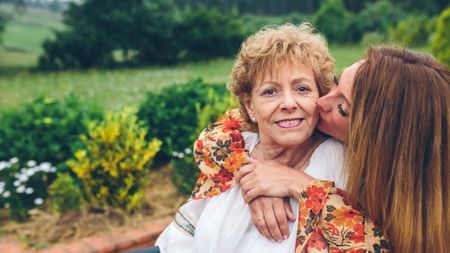Happy senior woman in a wheelchair with her daughter in the garden