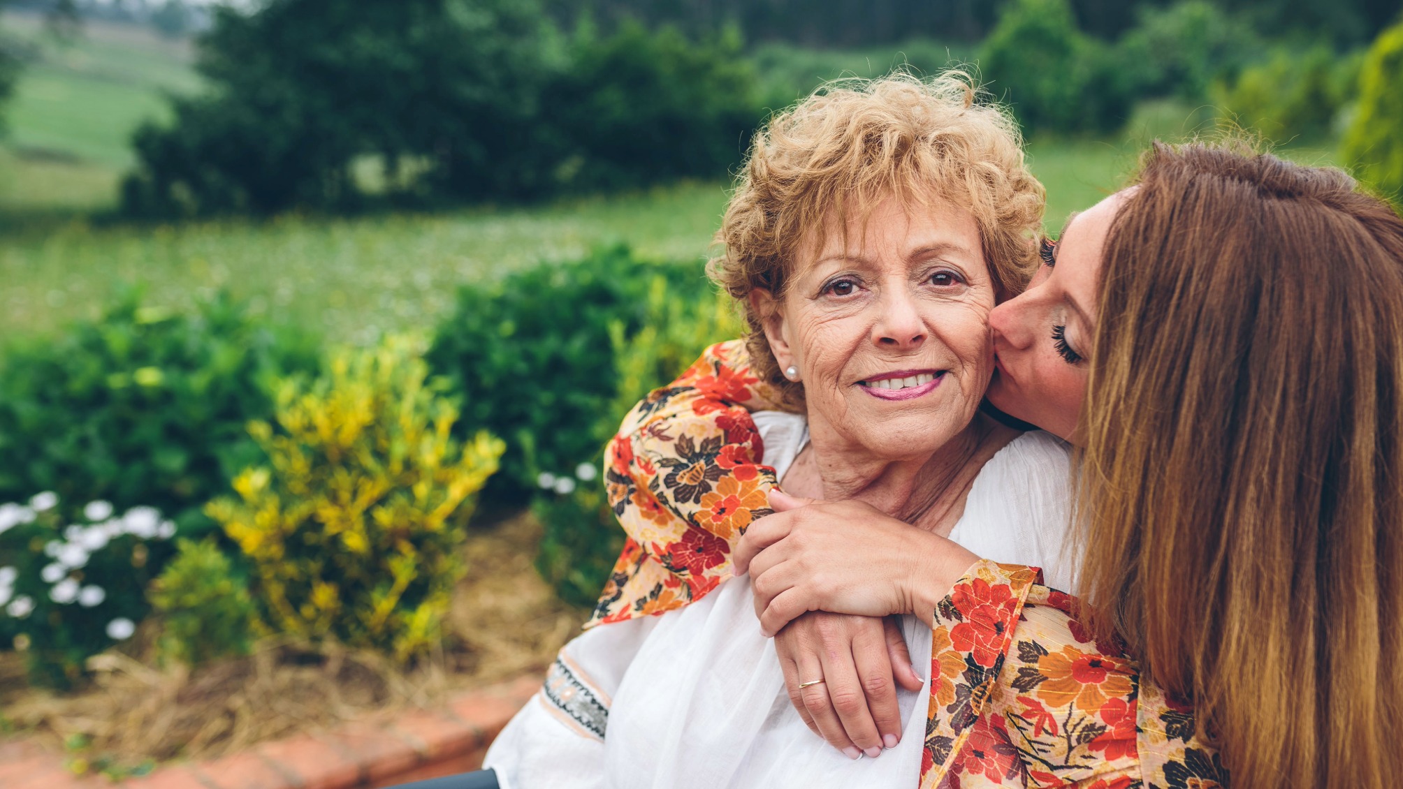 Happy senior woman in a wheelchair with her daughter in the garden