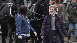 Una Stubbs on set with a horse behind her