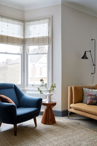 A living room with a navy blue armchair, and an ochre sofa