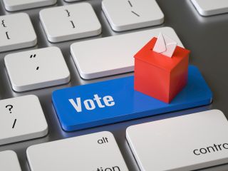 Vote key on computer with red ballot box atop keyboard. 