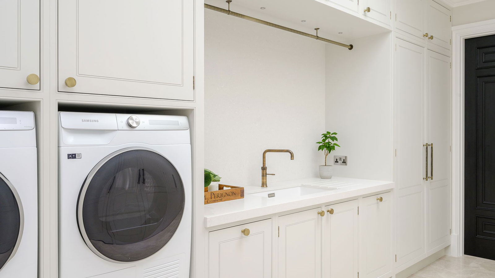 white utility room with washing machine and dryer and sink with brass tap