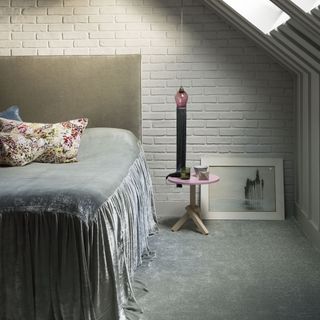 attic bedroom with white brick wall and bedside table and picture frame