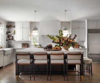 A large neutral kitchen with a island at the center and large upholstered bar stools for extra comfort