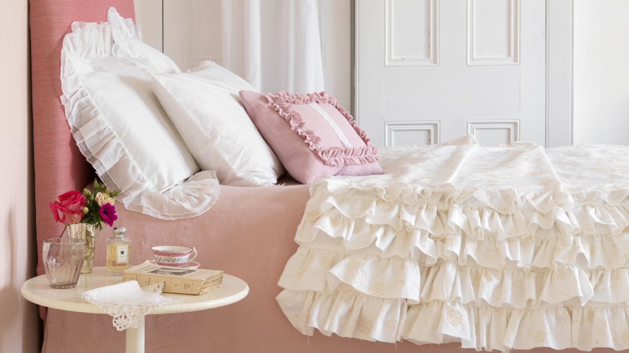 A bed with pink and cream ruffled bedding