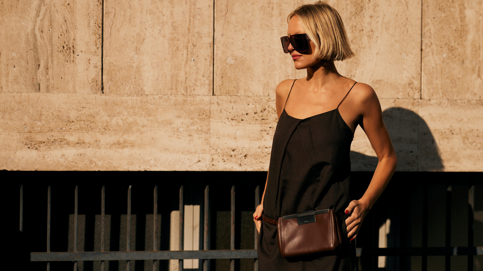 woman with short blonde hair wearing sunglasses black tank top and brown fanny pack