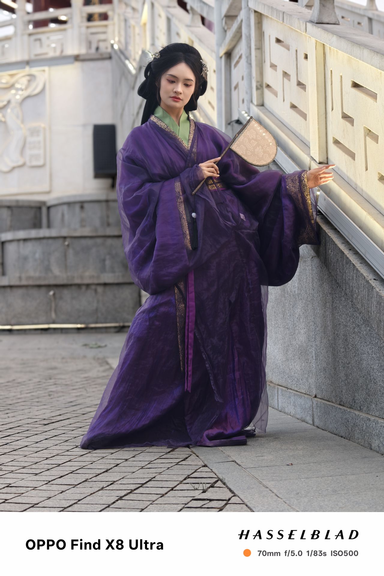 A person in traditional Chinese dress posing with a fan