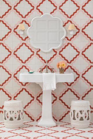 A white sink with a wall of orange and pink geometric tiles