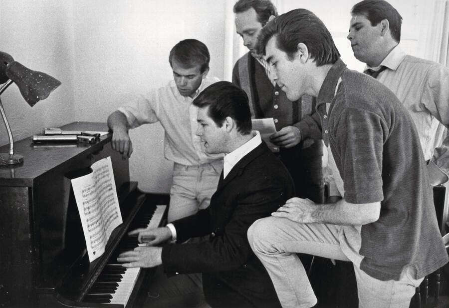 Al Jardine, Brian Wilson, Mike Love, Dennis Wilson and Carl Wilson of the rock and roll band "The Beach Boys" sing around a piano .
