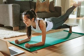 A woman doing core exercises at home in front of her laptop