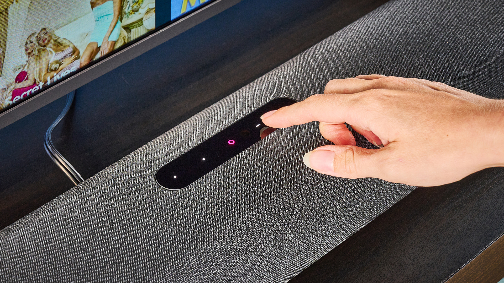 the bluesound pulse cinema soundbar photographed with a TV and the tom's guide blue background