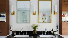 Double sink in black stone with two gold mirrors above and three scones evenly placed between