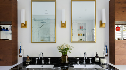 Double sink in black stone with two gold mirrors above and three scones evenly placed between