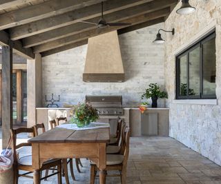 outdoor kitchen with stone walls and vintage table and chairs