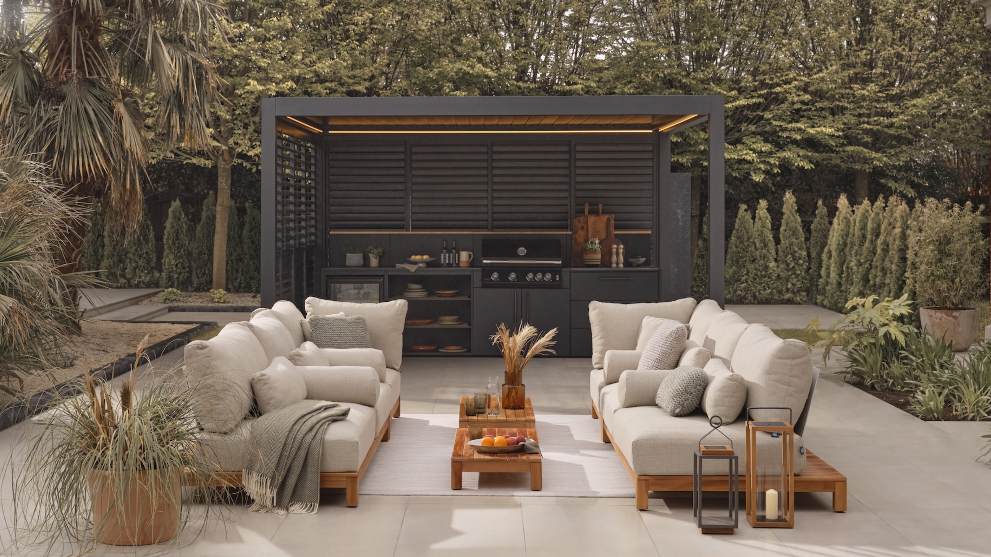 modern patio with two large couches, a coffee table, and a large outdoor kitchen underneath a pergola 