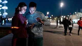 photo of man and woman stopping to check a phone midrun