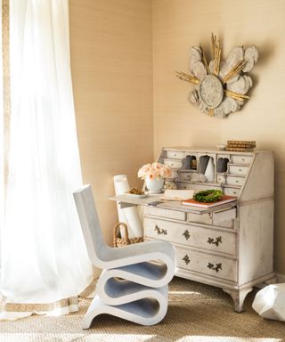 chalk paint bureau and contemporary scroll chair in room with with cream walls