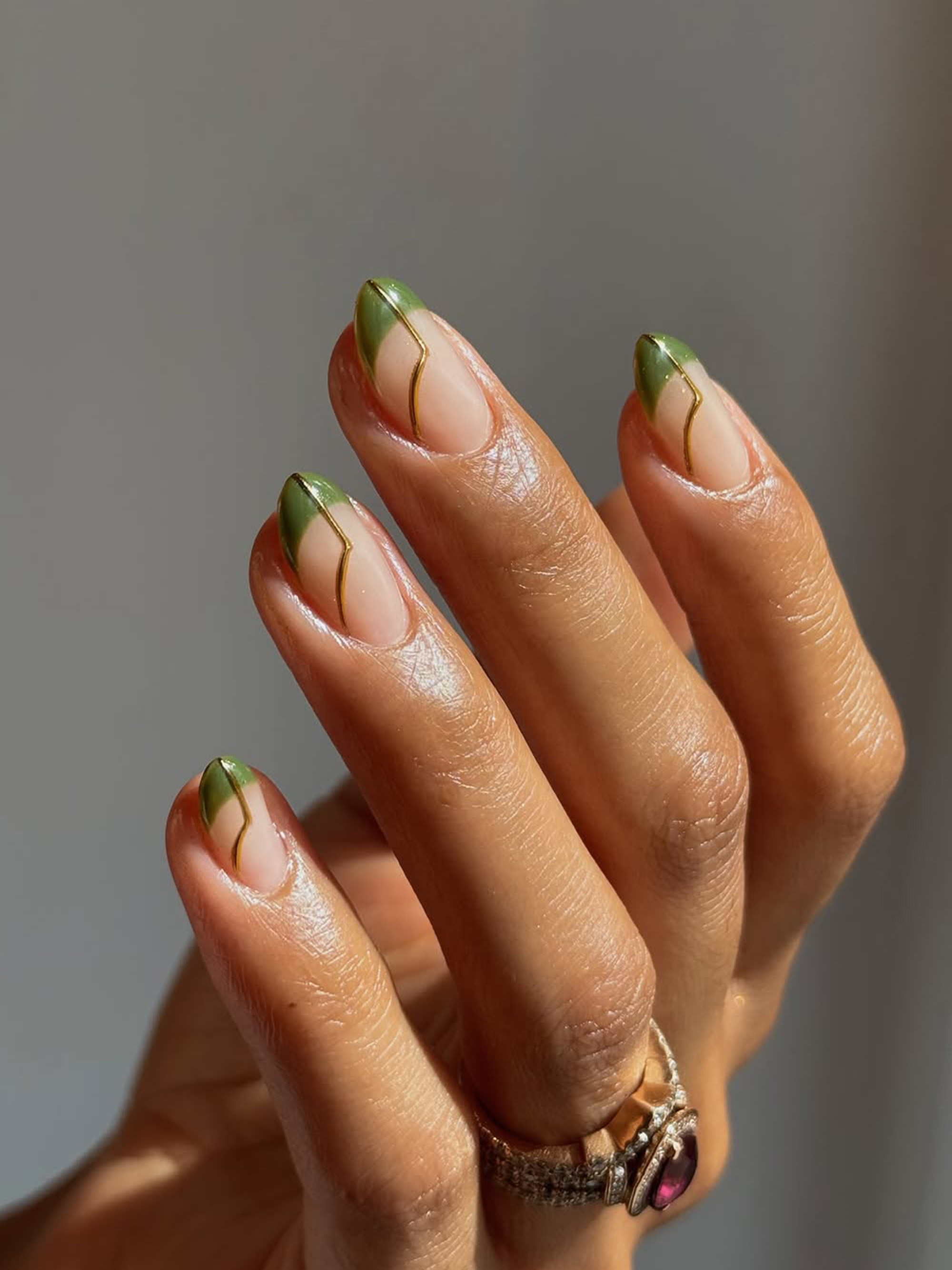 A green manicure with a minimalist, gold design by Queenie Nguyen