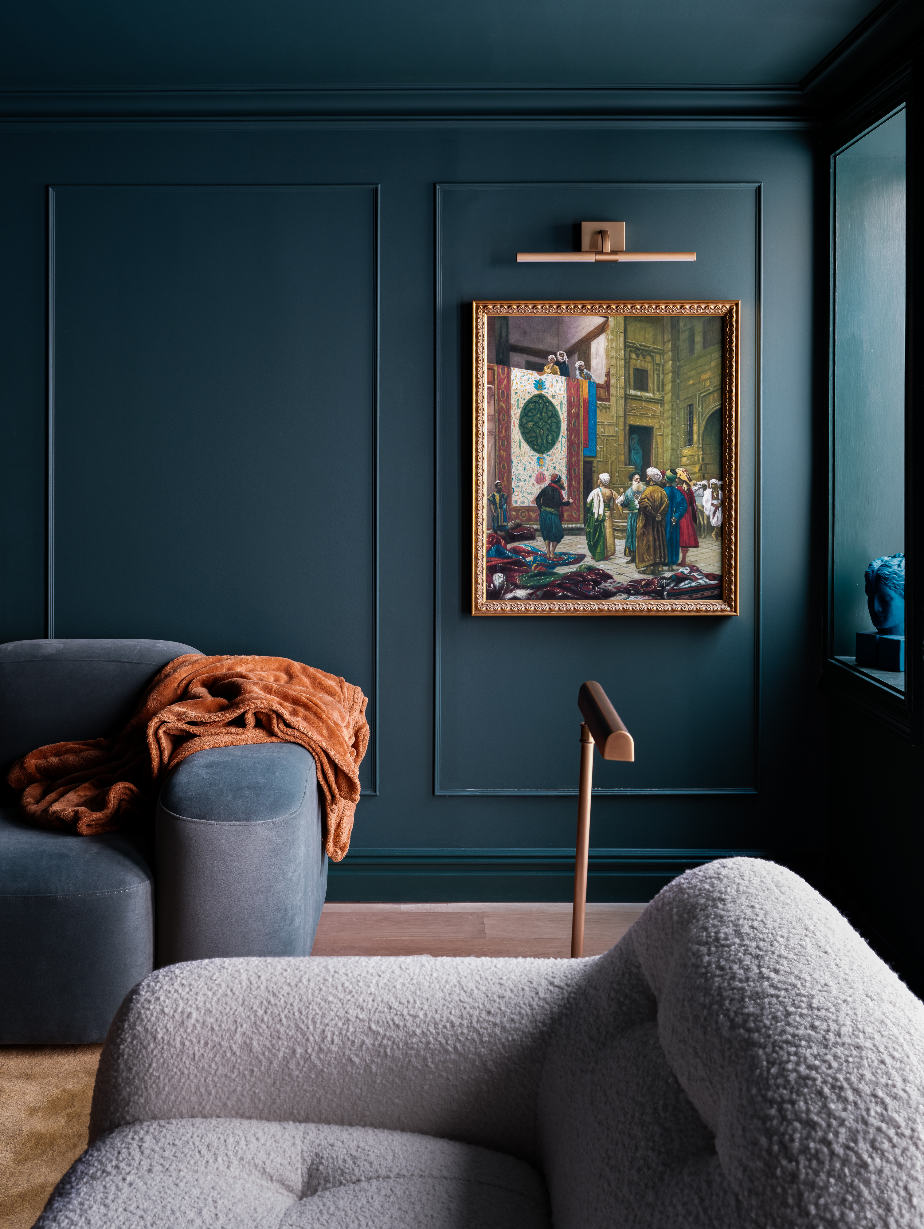 Navy blue living room featuring low-slung couches and wall art displayed in an ornate, antique-style frame