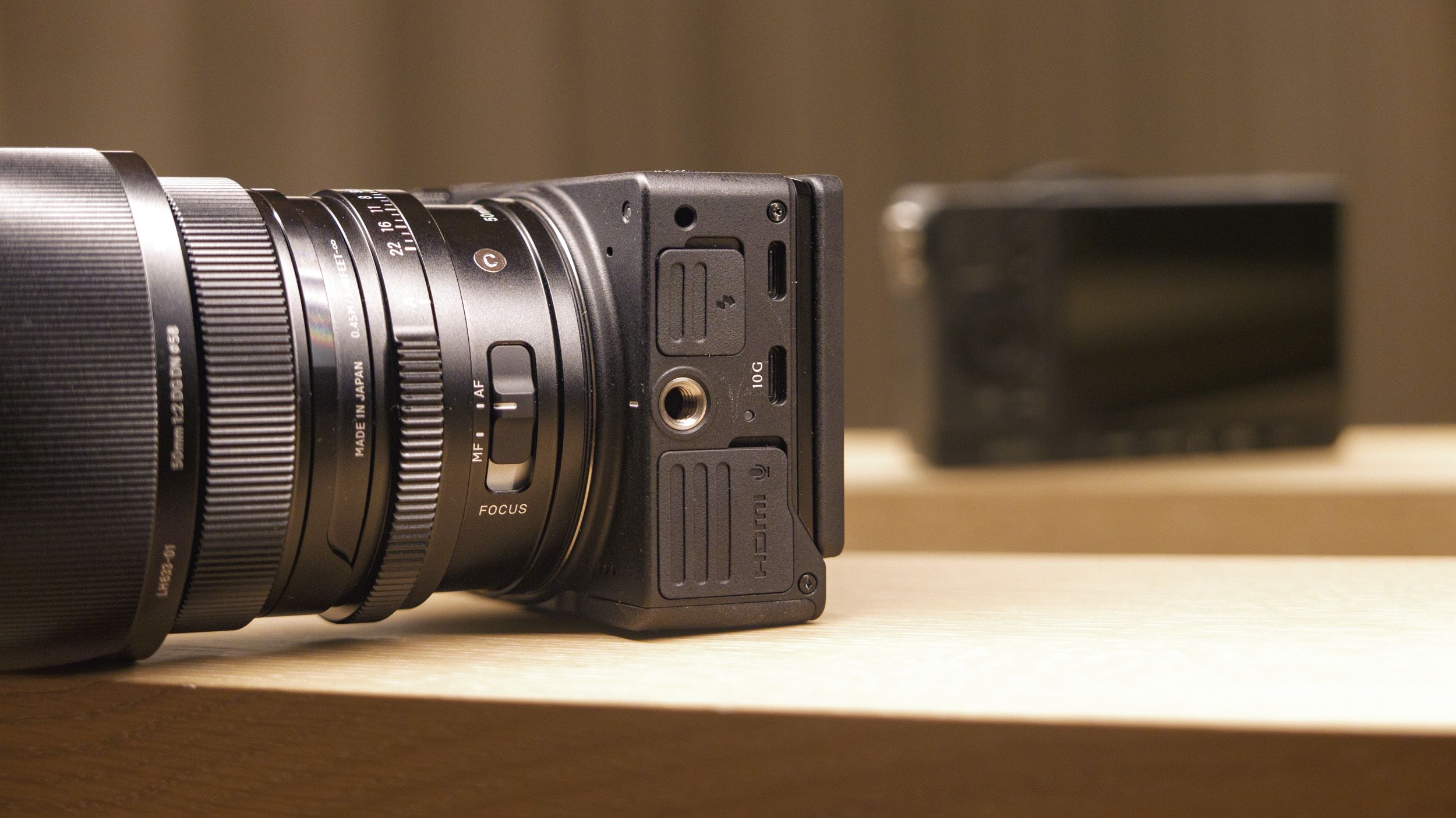 Sigma FP2 mirrorless camera with 50mm f/2 contemporary lenses attached, on a shelf, lit from above. Close up of its connection ports