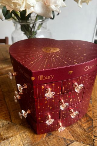 Charlotte Tilbury's beaty advent calendar is one of the best in the business and it's pictured here on a table with flowers in the background