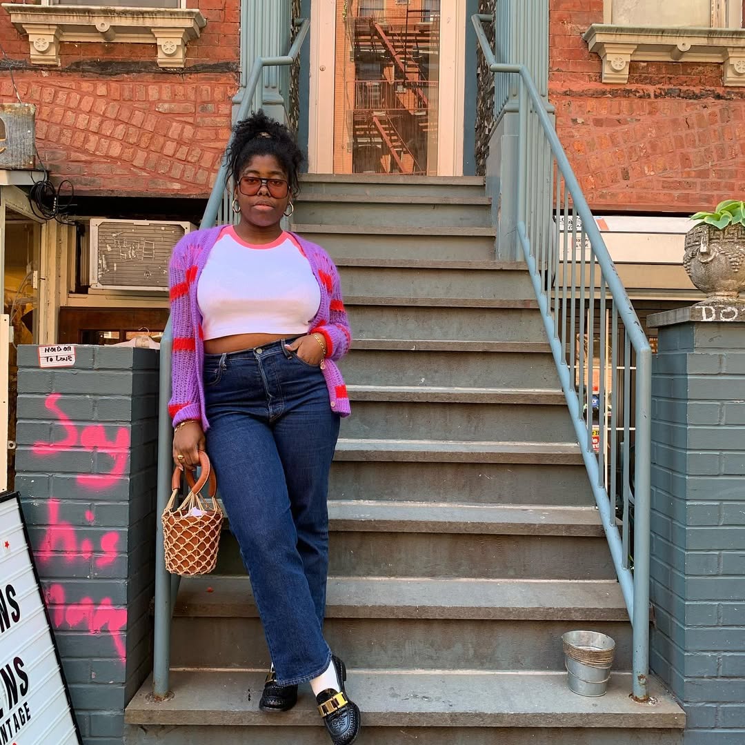 woman wearing cropped dark jeans and pink cardigan sweater