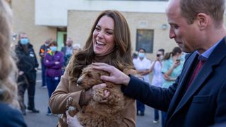 Kate Middleton, holding a dog, with Prince William by her side