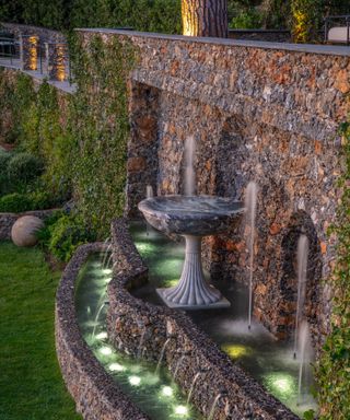 water fountain uplit in a terraced hillside garden with stone walls