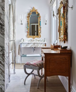 A bathroom with an antique wooden dressing table, and Italian-style gold mirrors
