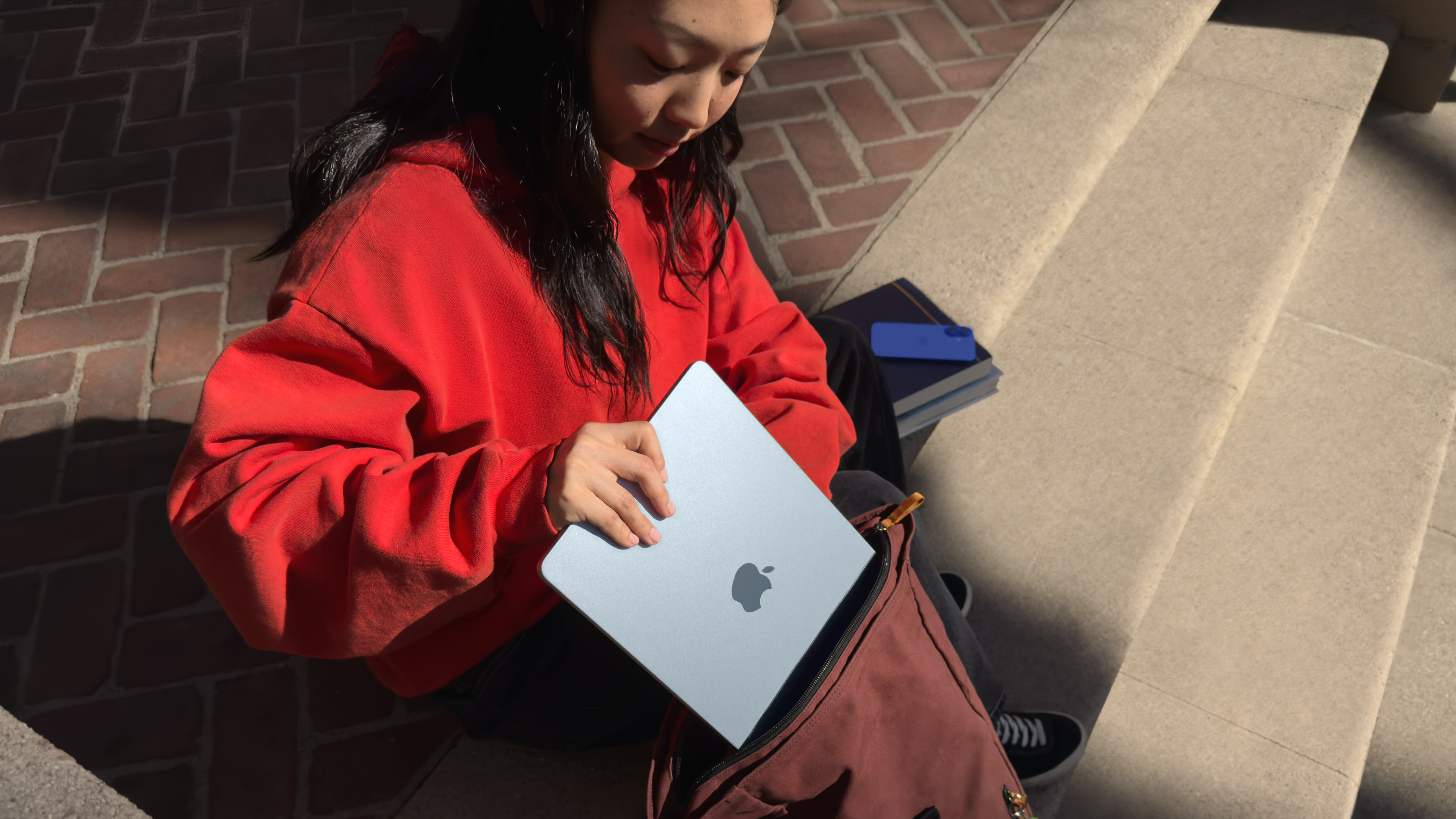 A person putting a MacBook Air M4 in a bag