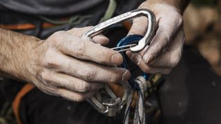 A climber's hands holding a carabiner