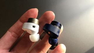 Bowers & Wilkins Pi7 S2 and S1 single earbuds held in a hand to show how similar they are