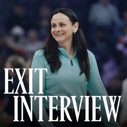 Sandy Brondello, smiling courtside in a teal zip-up top, during a WNBA game. The words &ldquo;Exit Interview&rdquo; appear in bold white text across the lower part of the image.